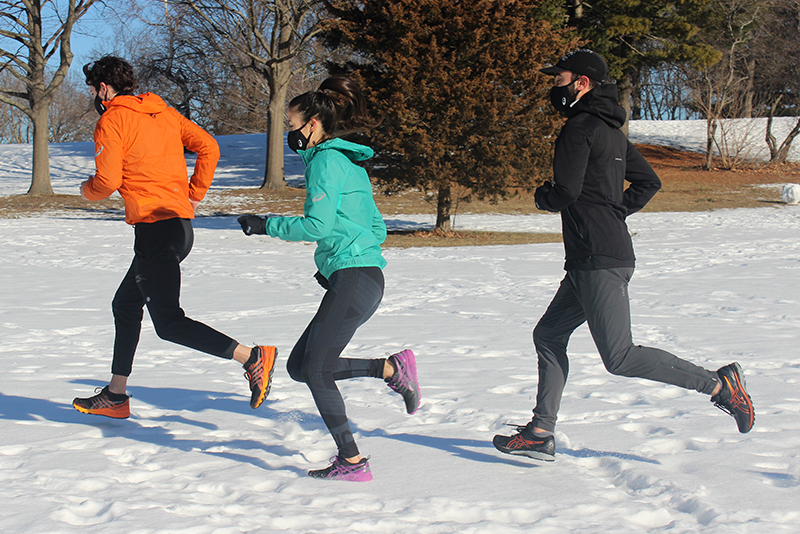 Three runners running on the snow in a field